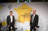Tadej Pogacar and Christian Prudhomme smiling in front of 2023 Tour de France map